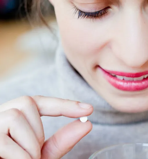 Девушка держит в руке таблетки подсластителя, от которой пучит живот
