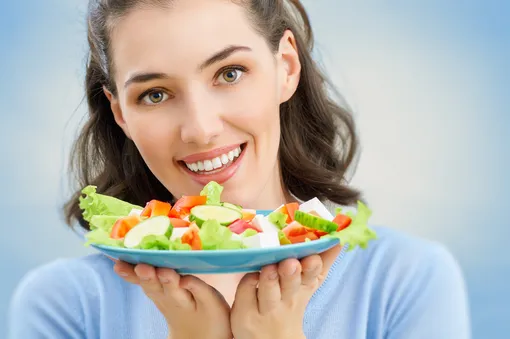 Девушка держит тарелку с греческим салатом, его можно есть, чтобы не поправляться