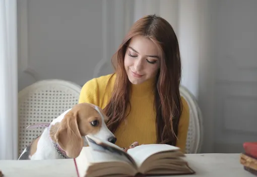девушка читает книгу с собакой