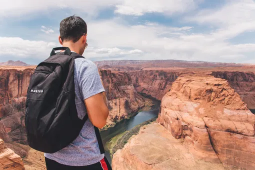 юноша с рюкзаком смотрит на каньон