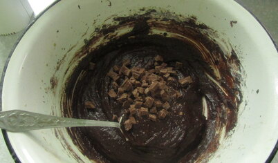Соединить вместе какао, сахар и масло. Добавить по одному яйца, перемешать. Шоколад нарубить на мелкие кусочки и добавить к массе.