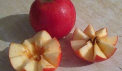 Яблоко разрезать по кругу ровными уголками, разделить на половинки и удалить семечки.