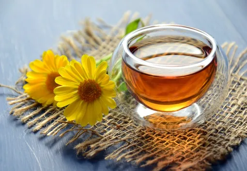 Чай в прозрачной чашке и желтые цветы