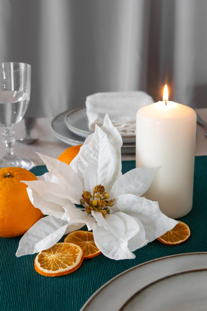 Стол, украшенный пуансеттией, свечами и мандаринами
