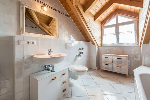 Ванная комната квартиры на чердаке с зеркалом и деревянным потолком