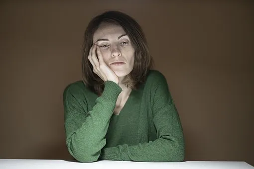 женщина в зеленом сидит подперев щеку
