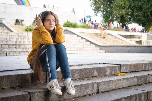 Девочка-подросток сидит на лестнице