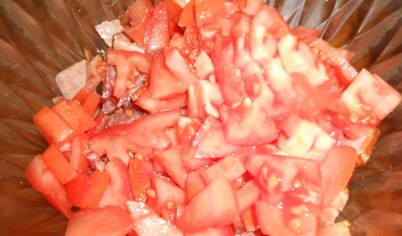 Добавить нарезанные помидоры. Салат порвать руками, лук мелко нарезать.