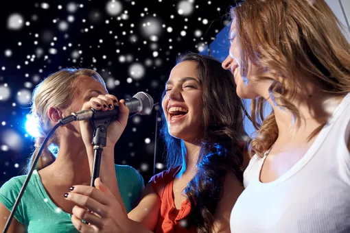 три девушки поют с микрофоном
