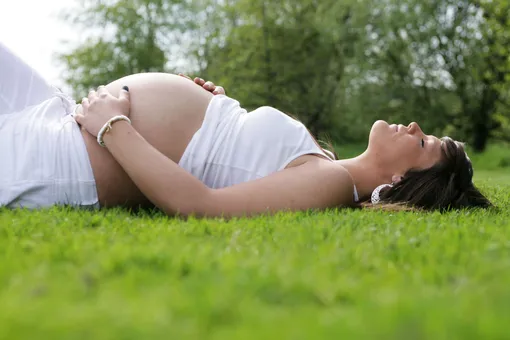 Беременная на 36 неделе беременности лежит на траве