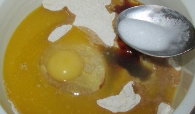 Добавить яйцо, мед, масло и соду, гашеную уксусом.