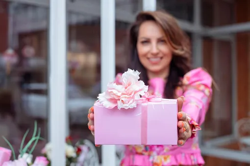 Девушка держит розовую коробку с подарком Поздравления с 8 марта в прозе