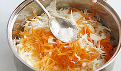 Сначала перетрите капусту с солью, стараясь ее не ломать. Добавьте морковь и сахар.
