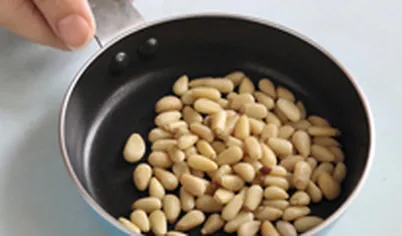 Обжарьте кедровые орехи на сухой сковороде.