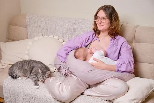 Женщина кормит малыша на подушке для кормления