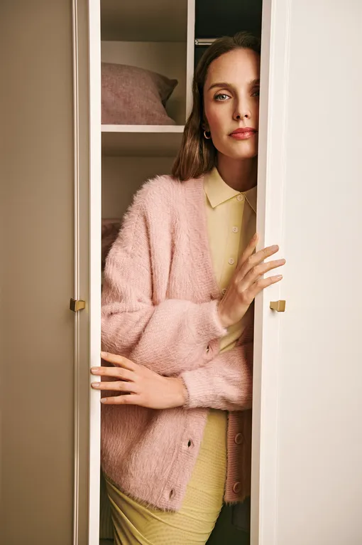Женщина в шкафу в розовом кардигане