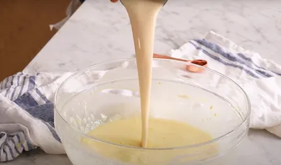В большой миске взбейте яйца. Добавьте сгущёное и топлёное молоко, ванилин и взбейте до однородного состояния. Перелейте яичную смесь в форму для флана с карамелью и накройте фольгой.
