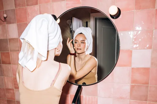 Девушка в чалме из полотенца у зеркала