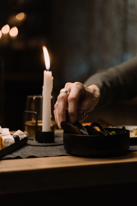 Мужская рука берет устрицу при свечах