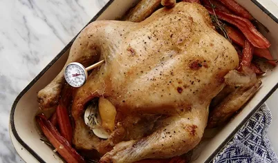 Как запечь курицу? Разогрейте духовку до 90 С. Поставьте курицу запекаться на 1.5 часа. Используя термометр для мяса, измерьте температуру, воткнув щуп в грудку курицы - она готова, если термометр показывает 70С. Достаньте форму с курицей из духовки, оставьте "отдыхать" на 45 минут. Если морковь еще осталась твержой, переложите курицу на тарелку, а противень с морковью доведите до готовноти, увеличив температуру духовки до 140 С.