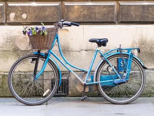 голубой велосипед с корзинкой стоит у стены