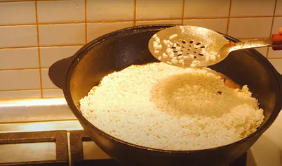 Засыпьте в кастрюлю рис для плова и осторожно разровняйте, не перемешивая. Утопите в рисе головку чеснока и вновь долейте воду так, чтобы она покрывала всю смесь на 2 см.

