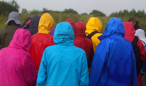 люди в разноцветных дождевиках стоят спиной