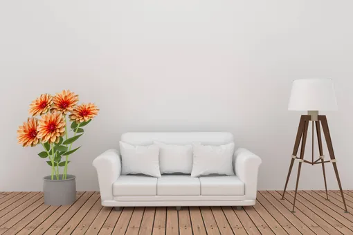 Украшение из цветов георгина с диваном и лампой в интерьере серой нейтральной комнаты