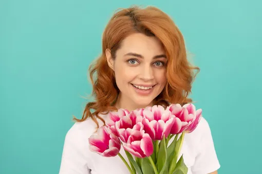 Девушка улыбается и держит тюльпаны Поздравления с 8 марта любимым девушкам