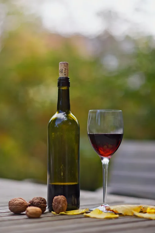 Бутылка красного вина на столе, бокал с красным вином