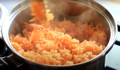 Засыпьте нарезанный лук и обжаривайте до готовности. Влейте томатный соус и куриный бульон. Доведите до кипения, уменьшите огонь до минимального. Накройте крышкой и варите около 20-25 минут. Готовый рис по-мексикански перемешайте вилкой.
