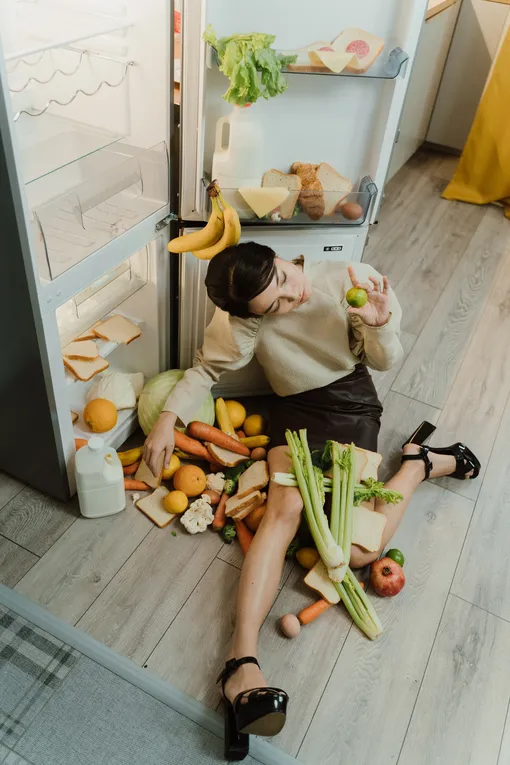 Девушка сидит у открытого холодильника фото