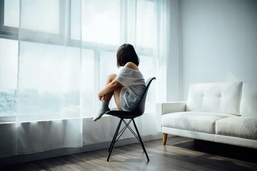 Девушка сидит около окна, депрессия, когнитивно-поведенческая терапия