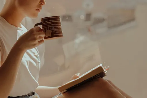 Девушка пьет чай и читает