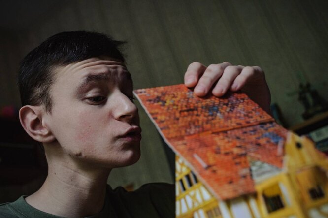 Виталий смотрит на картонную модель дома, которую он собрал вместе с мамой
