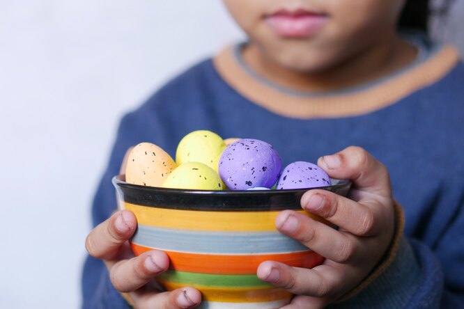 Мальчик держит миску с крашеными перепелиными яйцами