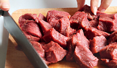 Мясо промокните салфеткой, некрупно нарежьте поперек волокон. Посолите и поперчите. В толстостенной кастрюле растопите шпик или разогрейте растительное масло, добавьте нарезанные лук и чеснок, обжарьте пару минут. Добавьте мясо, перемешайте и обжарьте все вместе, около 10 минут, помешивая.