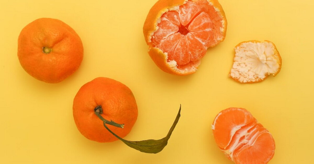 Происхождение мандарина. Мандарины. Грейпфрут на оранжевом фоне. Порезанный мандарин.