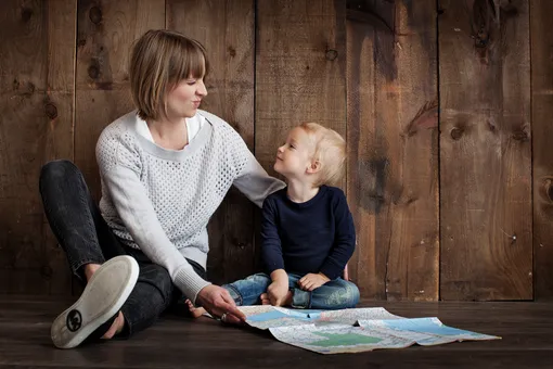 женщина с ребенком изучают карту сидя на полу