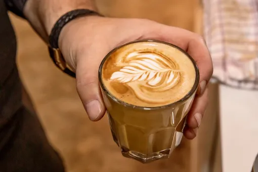 Кофе с рисунком на пенке в руке