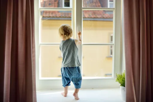 Ребенок на подоконнике пытается открыть окно
