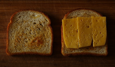 Разогреваем сковороду на среднем огне. Берём ломтик хлеба и смазываем его маслом. Кладём хлеб маслом вниз на разогретую сковороду, а сверху — ломтик сыра.

