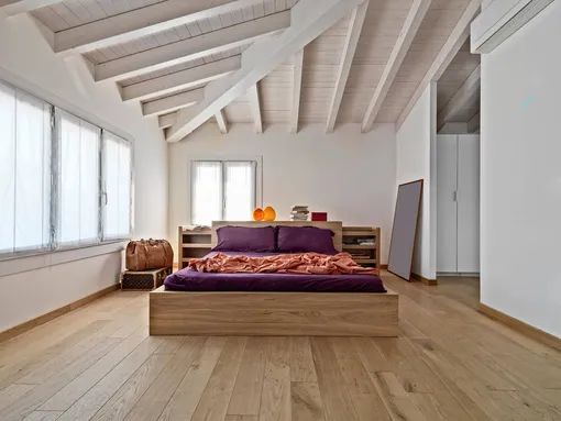 Современная спальня в мансарде с деревянной кроватью и деревянным потолком