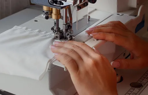 Женщина шьет на промышленной плоскошовной швейной машине