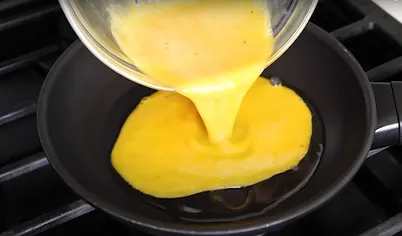 Приподнимите сковороду и влейте яично-молочную массу, распределив по поверхности. Накройте сковороду крышкой и уменьшите огонь. Омлет на молоке должен «прихватиться». При желании вы можете его перевернуть, как блинчик. 
