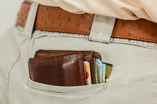 бумажник с картами и деньгами торчит из кармана брюк