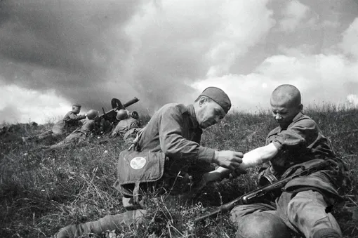 Санитар перевязывает руку раненому солдату