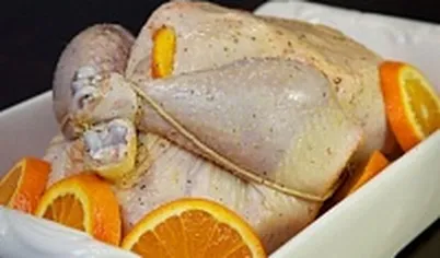 Свяжите ножки курицы. Если остались нарезанные апельсины, положите их в форму вместе с курицей. Запекайте курицу примерно 2-2,5 часа, время от времени поливая соком. Горячую курицу нарежьте на части и подавайте.