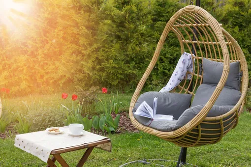Плетеное кресло-яйцо на подставке с серыми подушками
