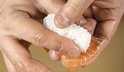 Смажьте лосось с внутренней стороны небольшим количеством васаби и выложите поверх риса. Уложите суши на тарелку. Подавайте с соевым соусом, васаби и имбирем.